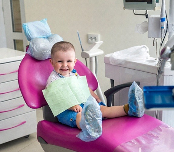 Boy with teddy bear in dental chair for age one dental visit