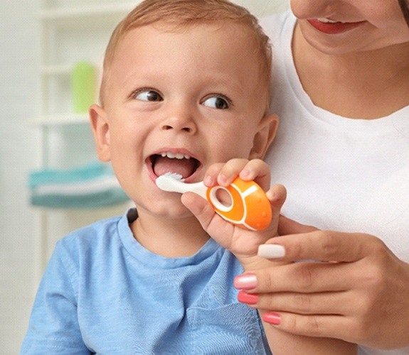 Young girl visiting dentist with father brushing her teeth