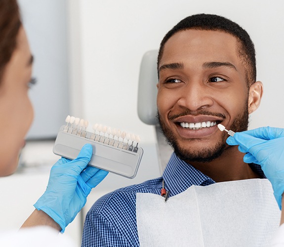 Patient's teeth compared with porcelain veneer color chart during cosmetic dentistry visit