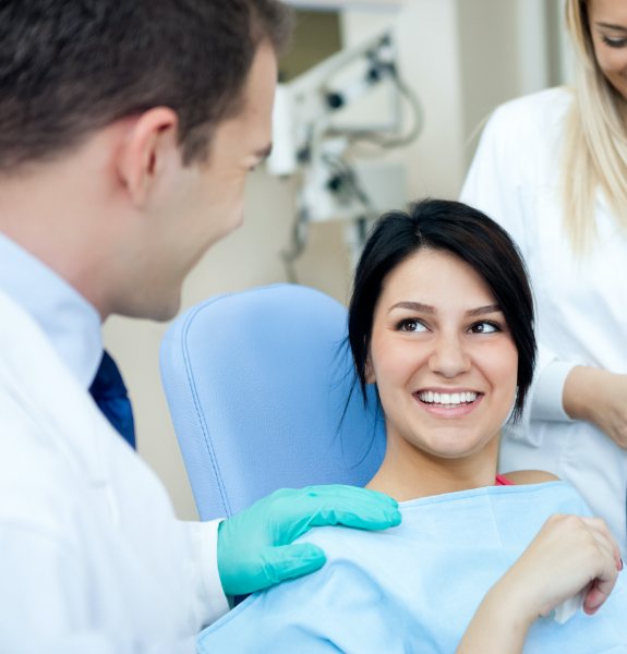 Woman in dnetal chair smiling at dentist