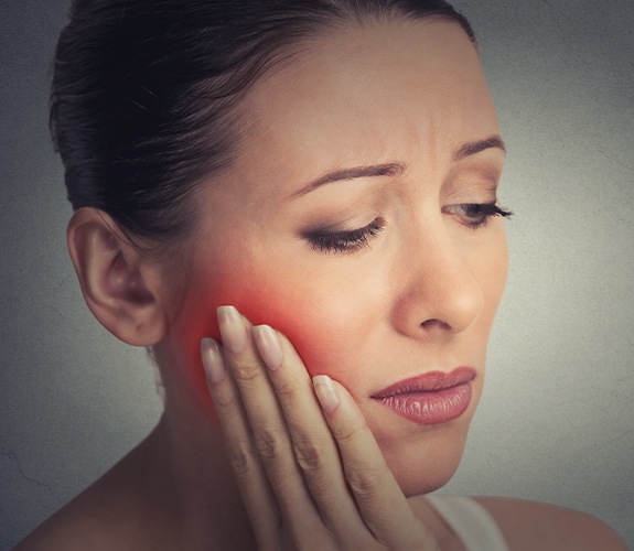 Woman in need of emergency dentistry holding jaw in pain