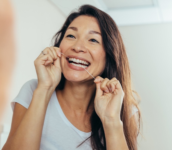 Woman flossing teeth to prevent dental emergencies