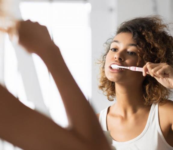 Woman cleaning her teeth after tooth extraction