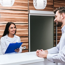 Patient paying for dental implants at dental office front desk