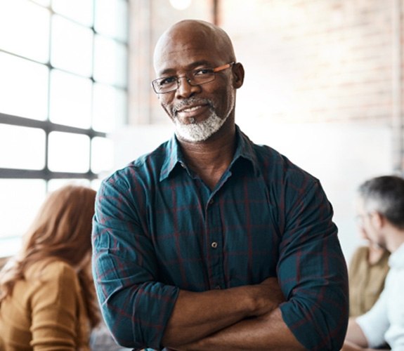 Man barely smiling and needing implant dentures 