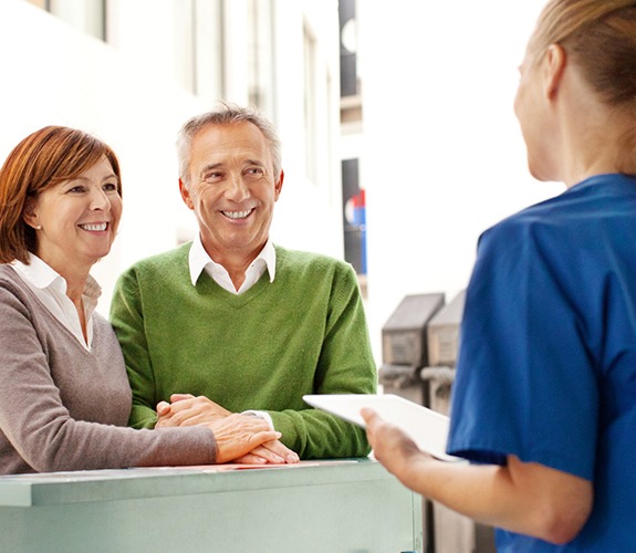 Man and woman discussing the cost of dental implant tooth replacement