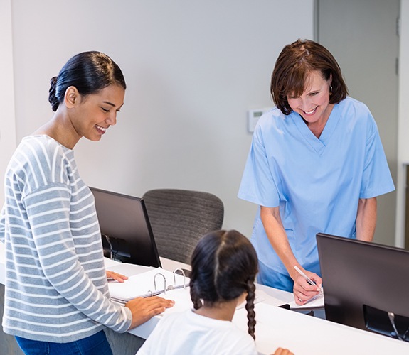 Dental team member helping mother and child understand how dental insurance works