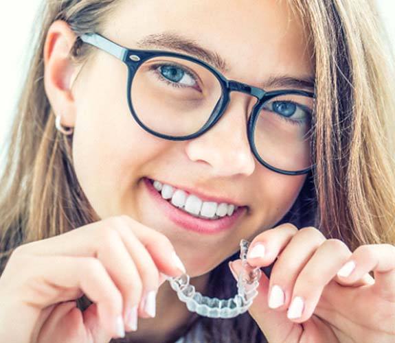 Girl inserting Invisalign Teen in Franklin Park