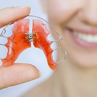 Woman holding a removable retainer for orthodontics in Franklin Park, IL