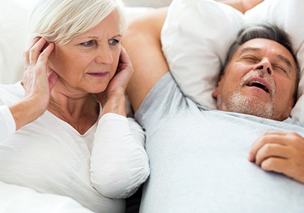 Frustrated woman next to snoring man in need of sleep apnea treatment