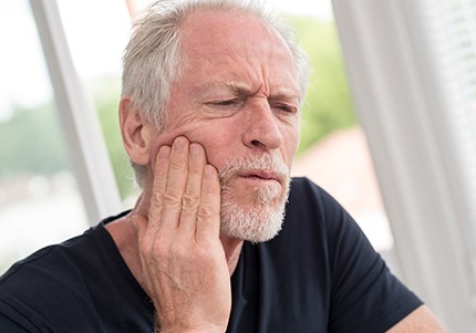 Man in need of emergency dentistry holding jaw