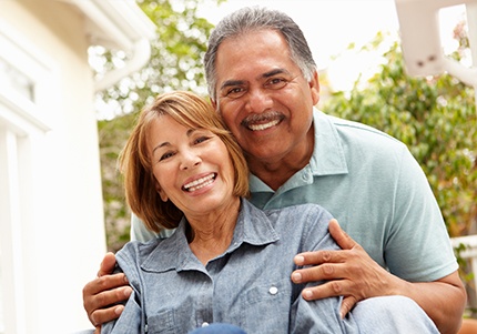 Man and woman sharing flawless smile after replacing missing teeth