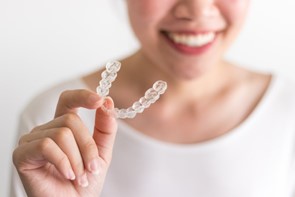 woman holding Invisalign aligner