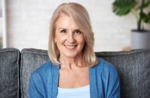 older woman wearing blue and smiling with dental implants